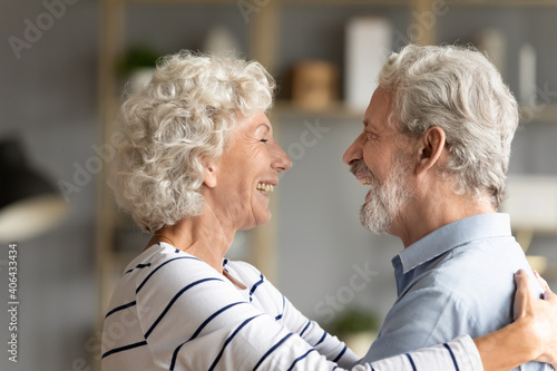 Obraz na plátně Happy hoary middle aged woman cuddling affectionate senior husband, missing glad to see after long separation
