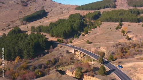 Drone shot of a car driving on an open road. Traveling through a mountain. photo