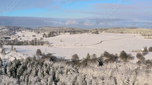 Lonely road  in a winter landscape, with snow everywhere, captured from above by a drone under the blue sky. photo