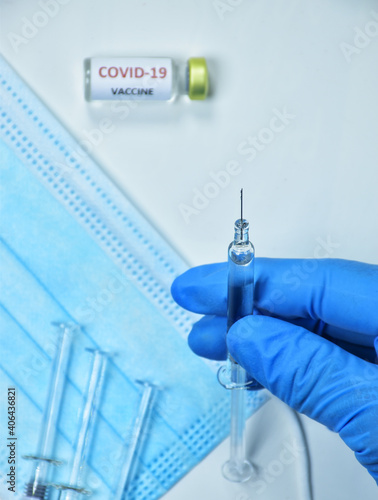 A doctor wearing blue gloves holds a bottle of COVID-19 vaccine.