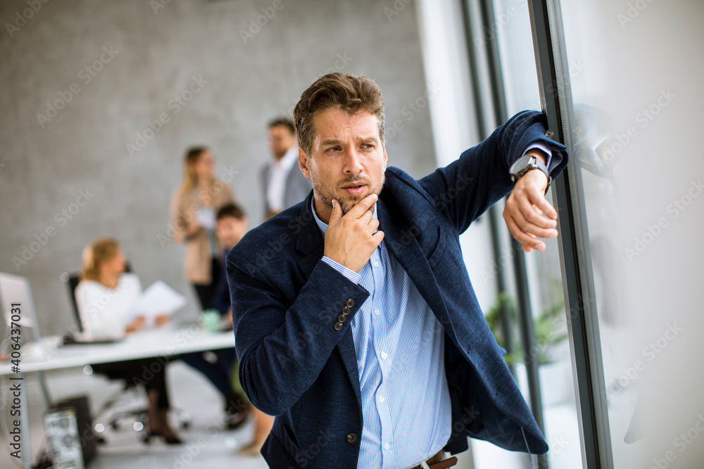 Business man feeling exhausted and stand at his working place in office Business man feeling exhausted and stand at his working place in office