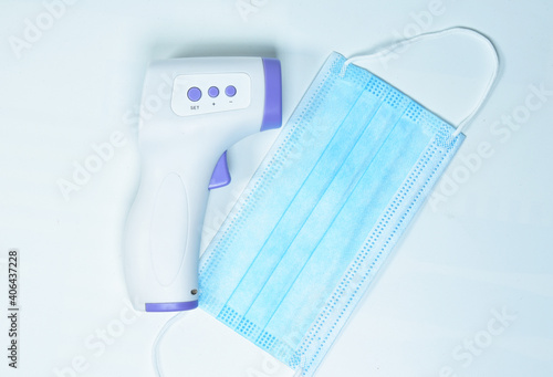 Infrared digital thermometer placed on the mask. On a white background
