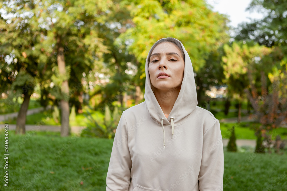 Portrait of a stylish fitness woman in a hood in a park outdoors. Fitness concept