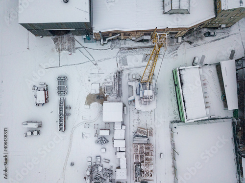 A crane at a snow-covered shipyard. Snowy day, blizzard. Aerial drone view.