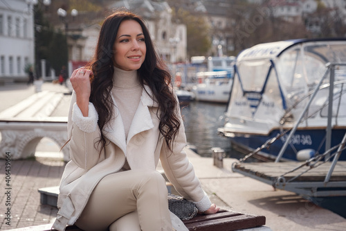 A woman in beige clothing enjoying the view of the sea on a warm, windy day.