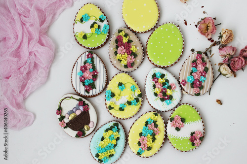 Easter colored gingerbread in the shape of an egg with a rabbit and flowers drawn on them.