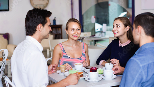 Cuadro en lienzo Happy cheerful friends meeting and drinking coffee with pastry at cafe