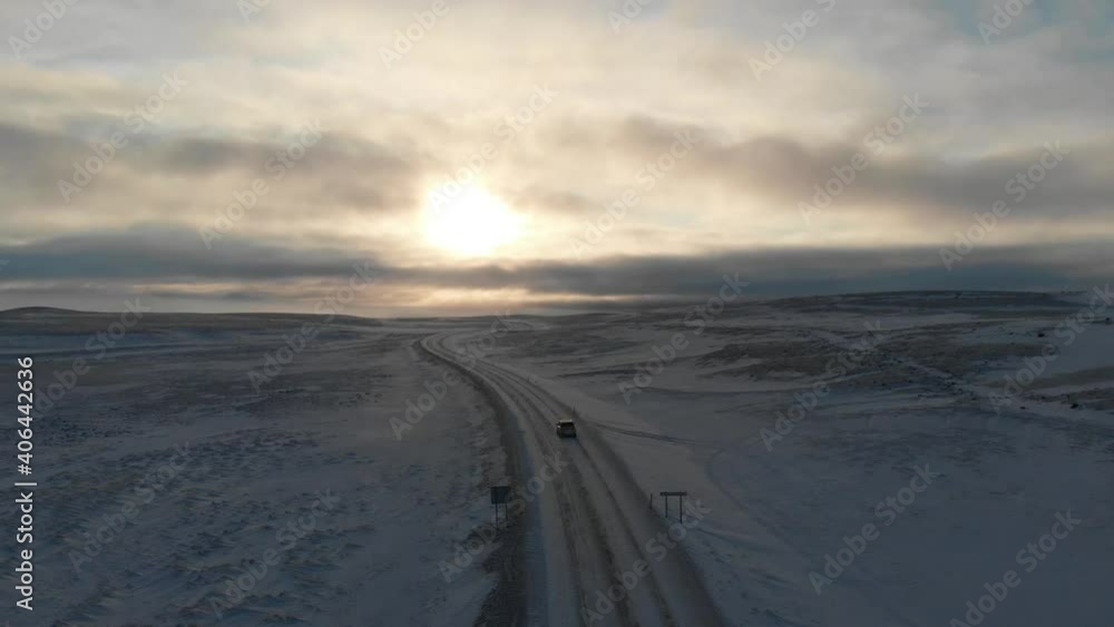 Cinematic Aerial View of Car on Empty Icy Road in Highland of Iceland at Sunset Sunlight. Stunning Snowy Landscape, Drone Shot Cinematic Aerial View of Car on Empty Icy Road in Highland of Iceland at Sunset Sunlight. Stunning Snowy Landscape, Drone Shot