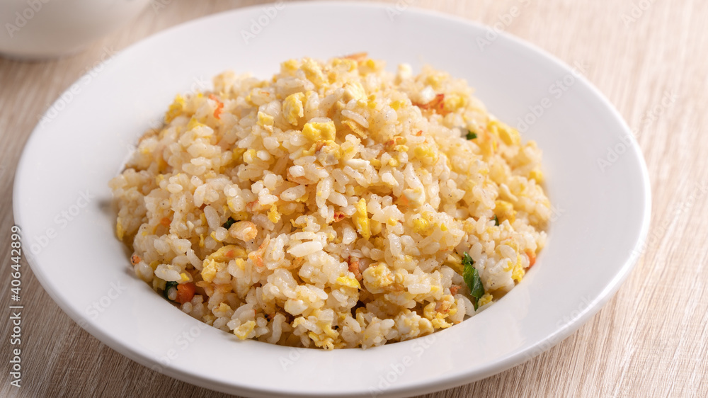 Chinese fried rice in white plate on bright wooden table background. Chinese fried rice in white plate on bright wooden table background.