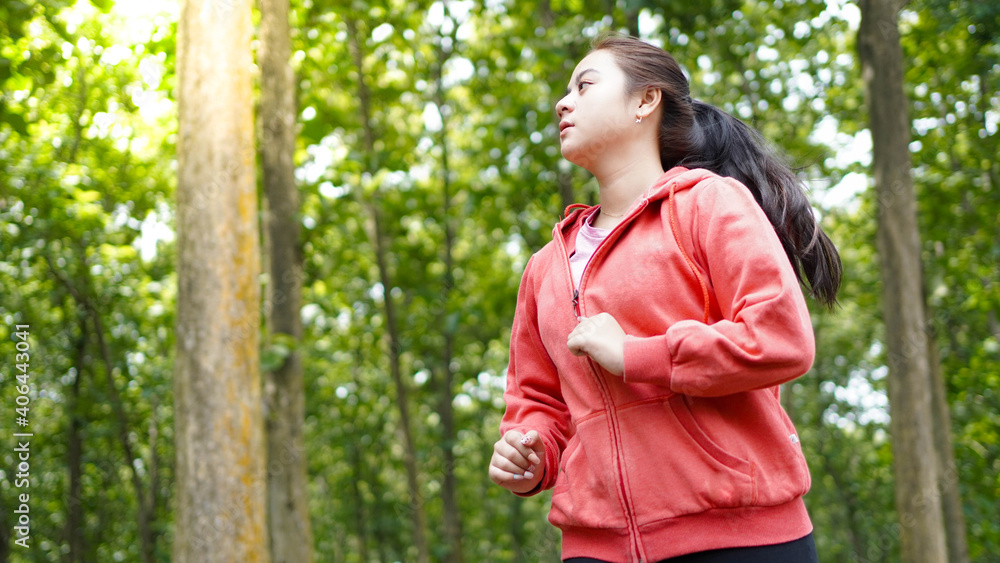 Asian woman running in forest wearing jacket Asian woman running in forest wearing jacket