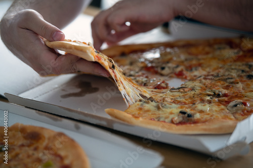 Mann nimmt ein Stück Funghi Pizza aus dem Pizzakarton- Konzept Fast Food, Pizza essen photo