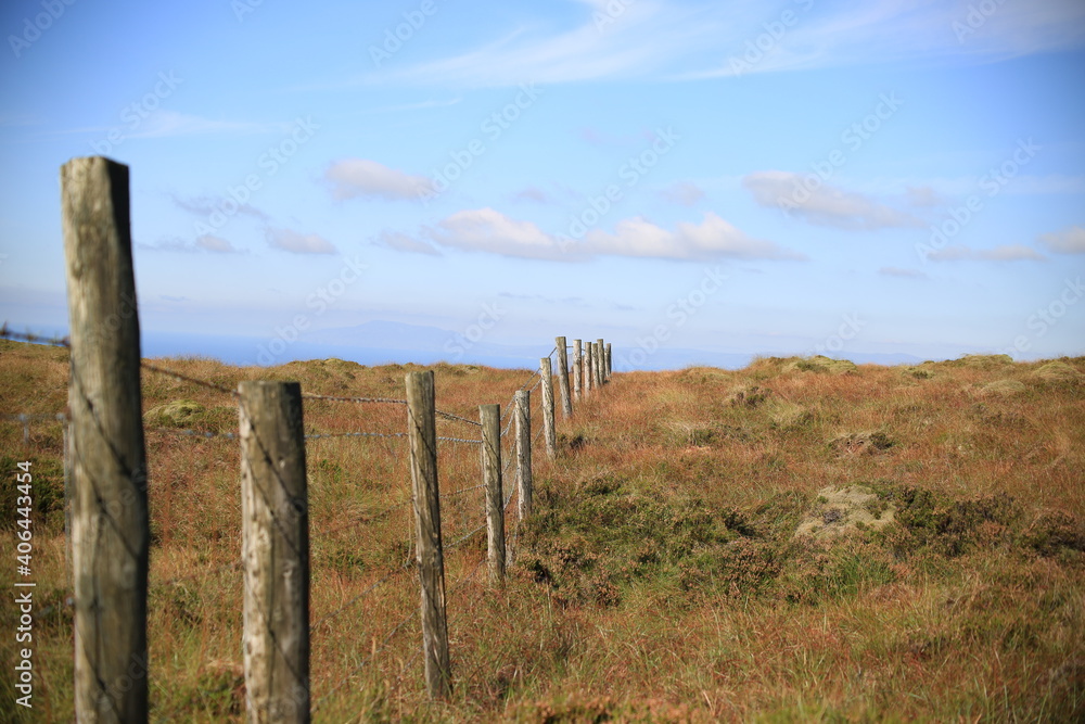 Obraz premium Fencing across countryside under blue skies