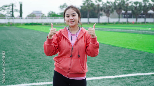 Fotografie Asian runner woman wearing jacket and earphone OK gesture