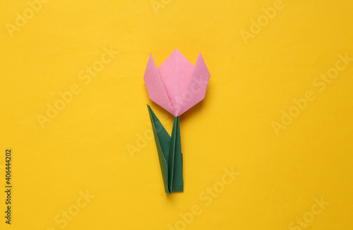 Pink paper tulip on yellow background. 8 March, women's day concept. Handmade origami tulip. Top view. Minimalism #406444202