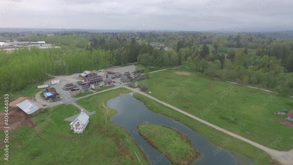 Aerial drone shot of a western farm town in British Columbia. Pond, forest, roads, buildings and industrial farmland visible. Aerial drone shot of a western farm town in British Columbia. Pond, forest, roads, buildings and industrial farmland visible.