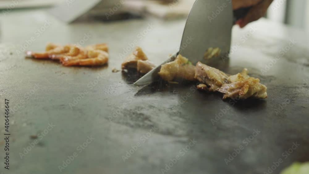 Chef Carefully Slicing Meat Into Bite-Size Pieces In Hot Stone Grill - close up shot Chef Carefully Slicing Meat Into Bite-Size Pieces In Hot Stone Grill - close up shot