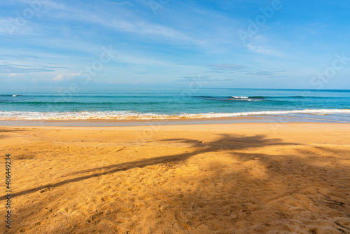 View of coconut tree shadow  blue sky  blue sea  small wave and yellow sand that is signature of beautiful seascape scene at Phuket Province  Thailand in the morning of holiday.