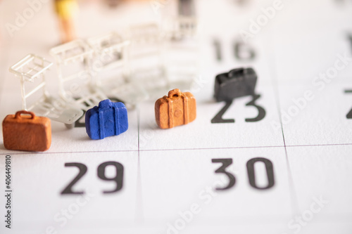 Miniature Tourists standing on the calendar with bags