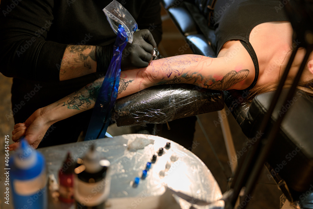 Obraz premium Professional male bearded caucasian tattoo master is working in cozy atmospheric studio