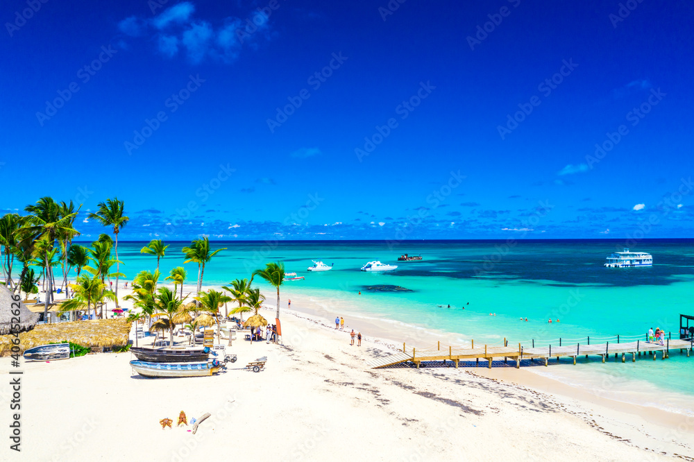 Aerial drone view of beautiful atlantic tropical beach with palms, straw umbrellas and boats. Bavaro, Punta Cana, Dominican Republic. Vacation background.