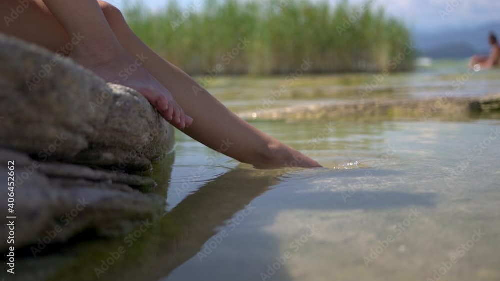 Dipping feet in lake water puddle on a hot summer day, on Jamaica Beach, Sirmione, Lago Garda, Lake Garda, Italy. SLOW MOTION Dipping feet in lake water puddle on a hot summer day, on Jamaica Beach, Sirmione, Lago Garda, Lake Garda, Italy. SLOW MOTION