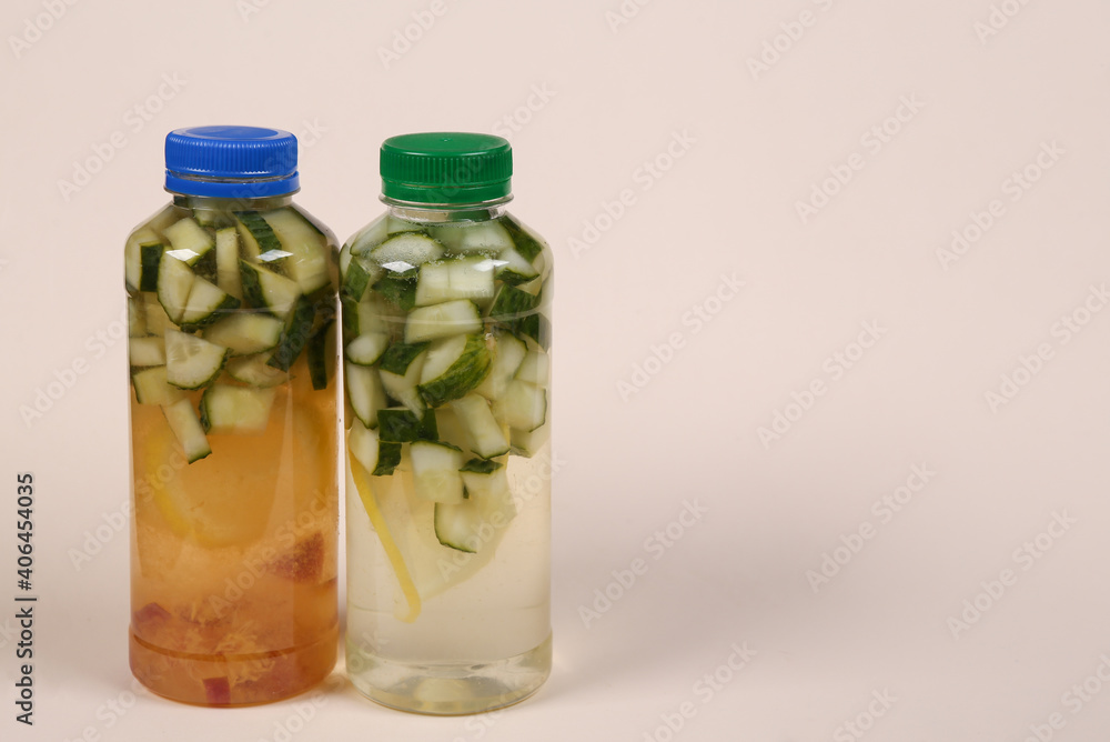Detox drink, cucumber lemonade bottles on beige background Detox drink, cucumber lemonade bottles on beige background