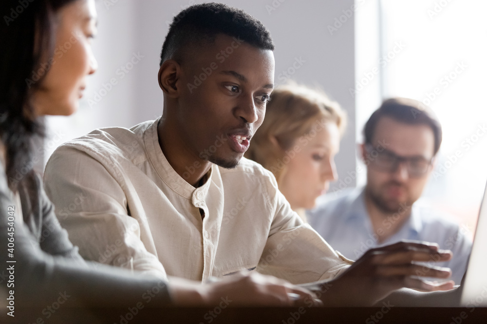 Focused young african american employee explaining computer app to asian mature colleague, working in pairs on online project in office. Motivated diverse coworkers analyzing electronic documents. Focused young african american employee explaining computer app to asian mature colleague, working in pairs on online project in office. Motivated diverse coworkers analyzing electronic documents.