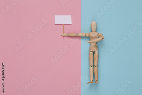 Protesting activist wooden puppet with blank banner on pink blue pastel background. Meeting. Defending your rights. Top view