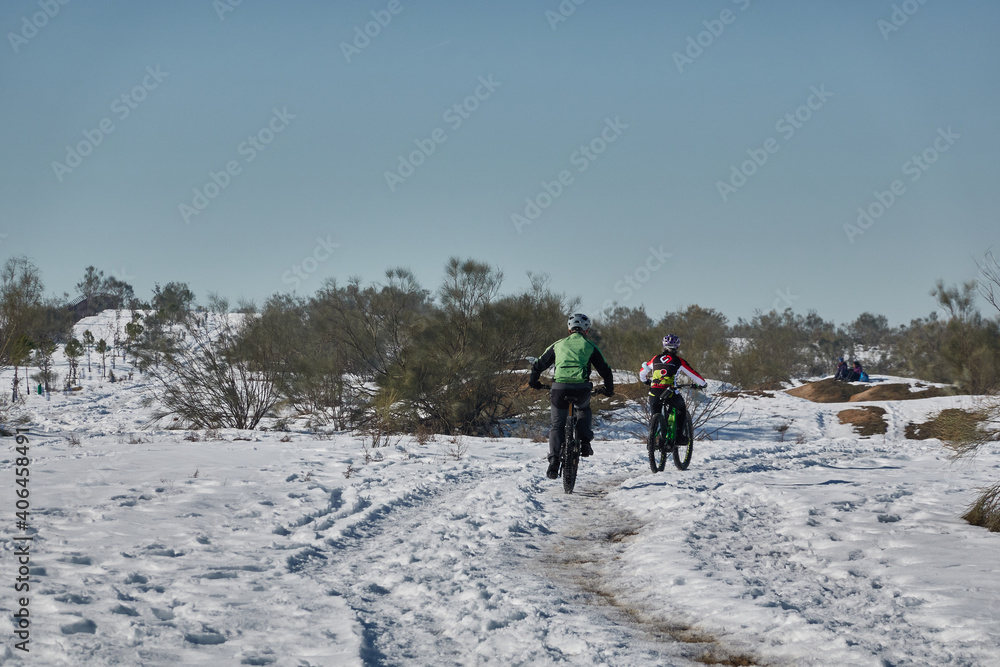 Two cyclists in the Meaques-Retamares environment after the snowfall caused by storm Filomena in Madrid. Spain
