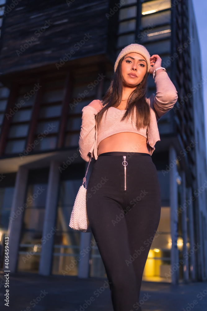 A young brunette Caucasian posing in the city on a winter night, wearing a pink knitted sweater and hat. Street style fashion A young brunette Caucasian posing in the city on a winter night, wearing a pink knitted sweater and hat. Street style fashion