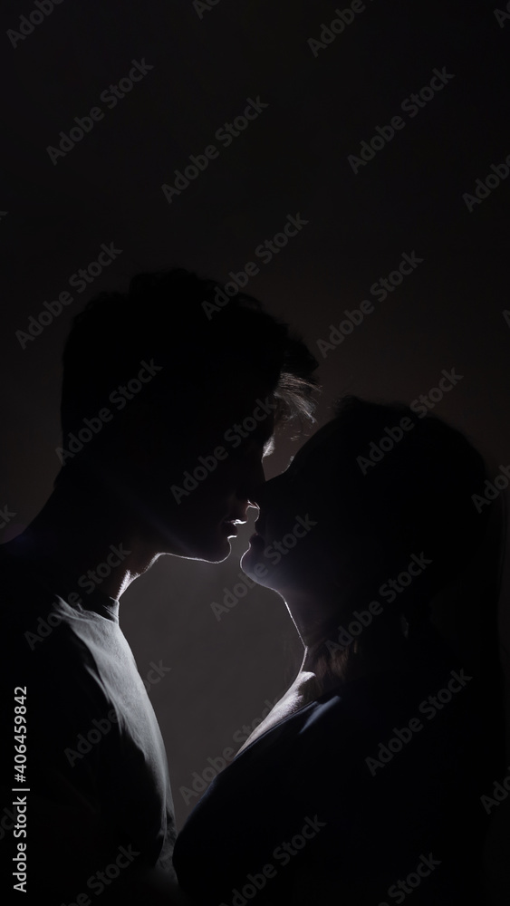 Side view of happy young couple celebrating Valentine's Day together. Beautiful couple is kissing. Beautiful young couple smiling while sitting face to face