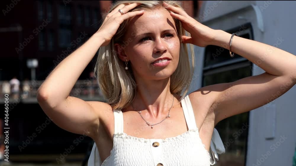 Ein Portrait einer schönen Blondine im weißen Sommerkleid. Sie schaut um, fasst ihre Haare an und posiert. Ein Portrait einer schönen Blondine im weißen Sommerkleid. Sie schaut um, fasst ihre Haare an und posiert.