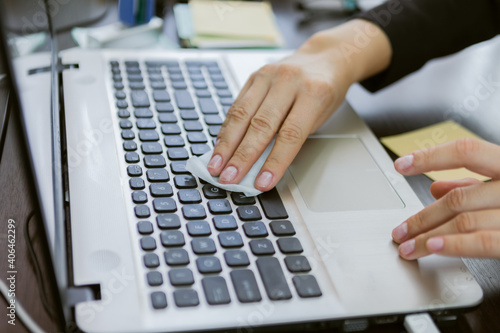 Business woman wipes laptop keyboard with damp cloth in office