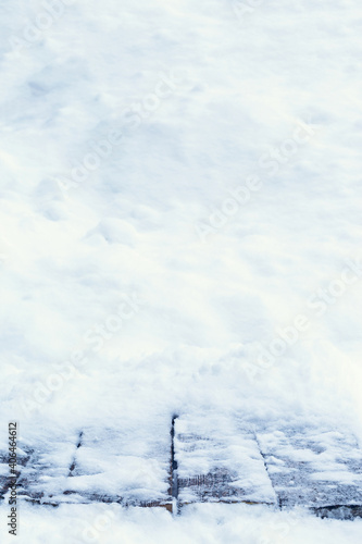 Top of the old wooden table covered with snow. Natural real snow on old wooden boards. Copy space. Vertical composition.