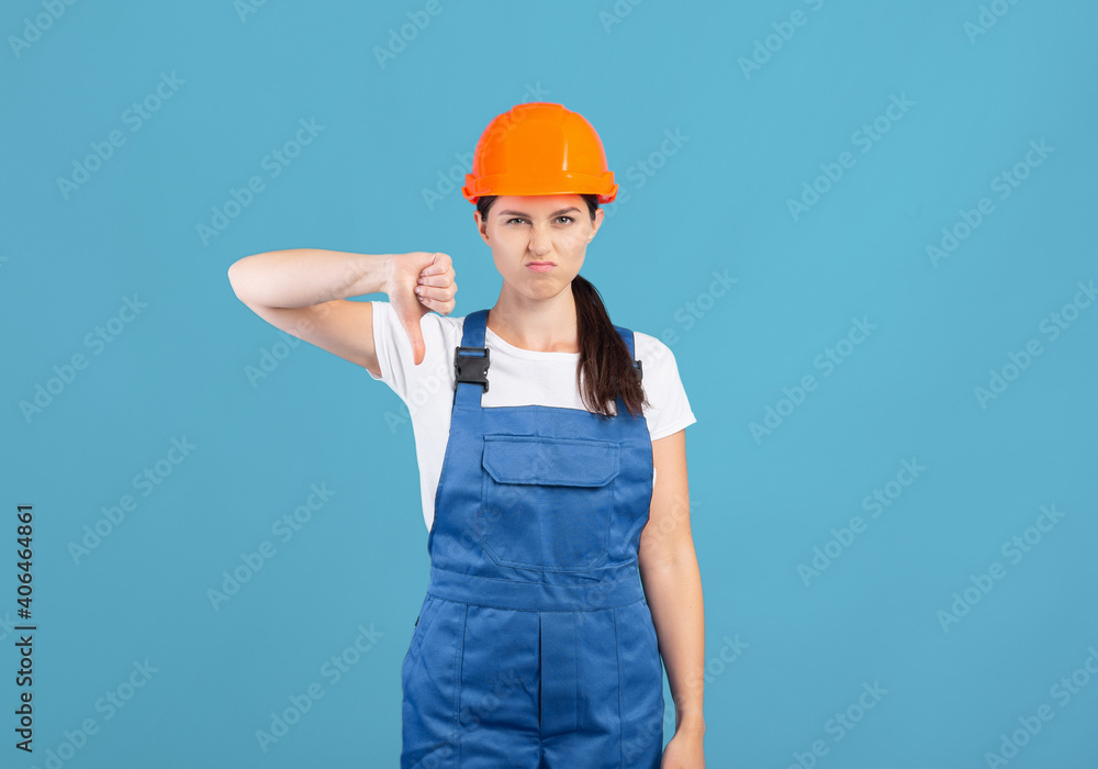 Portrait Of Young Handywoman Lady In Hardhat And Coveralls Showing Thumb Down Portrait Of Young Handywoman Lady In Hardhat And Coveralls Showing Thumb Down