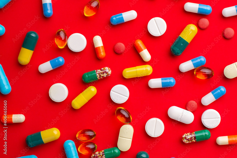 Close up of colorful pills and capsules of different colour and shape on red background. Medicine and pharmacy concept. Close up of colorful pills and capsules of different colour and shape on red background. Medicine and pharmacy concept.