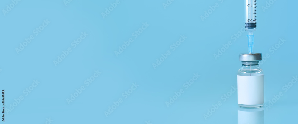 Vaccine in a bottle with a syringe on a blue background.The concept of medicine, healthcare and science.Coronavirus vaccine.Copy space for text.Banner Vaccine in a bottle with a syringe on a blue background.The concept of medicine, healthcare and science.Coronavirus vaccine.Copy space for text.Banner