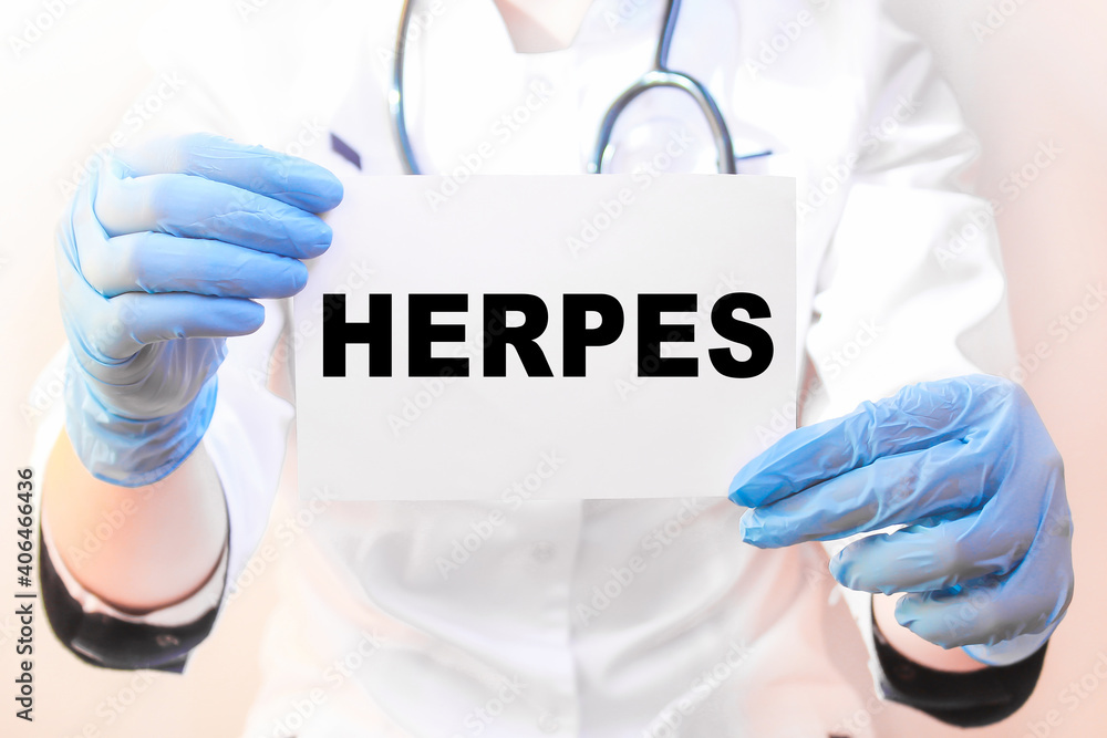 The doctor's blue - gloved hands show the word HERPES - . a gloved hand on a white background. Medical concept. the medicine