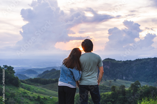 Happy young couple traveler relaxing and looking at the beautiful sunset on the top of mountain