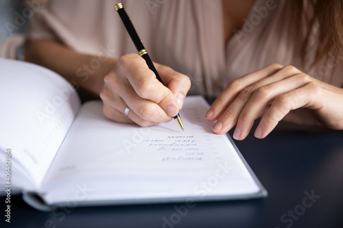 Close up businesswoman writing in notebook  planning workday  meetings  entrepreneur managing time  sitting at table  student making note during lecture  preparing for exam  handwriting