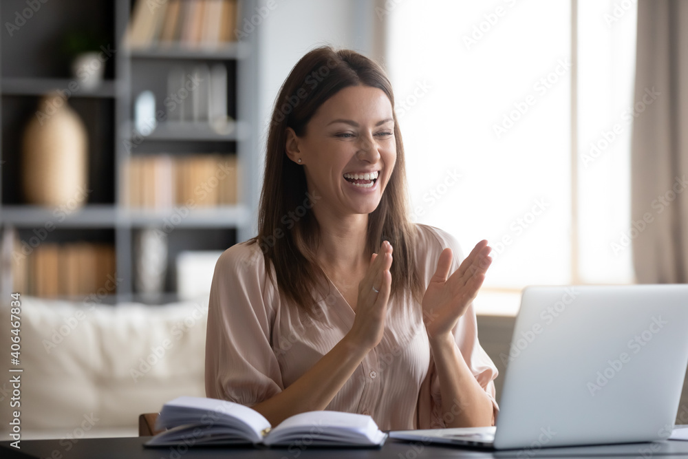 Overjoyed young woman looking at laptop screen, surprised by good news, looking at laptop screen, sitting at work desk at home, excited female celebrating success, clapping hands, online win Overjoyed young woman looking at laptop screen, surprised by good news, looking at laptop screen, sitting at work desk at home, excited female celebrating success, clapping hands, online win