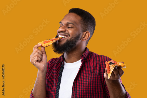 Black Guy Eating Pizza Slice With Eyes Closed, Yellow Background