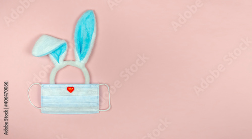 Rabbit ears on a pink background in a medical mask.Easter 2021