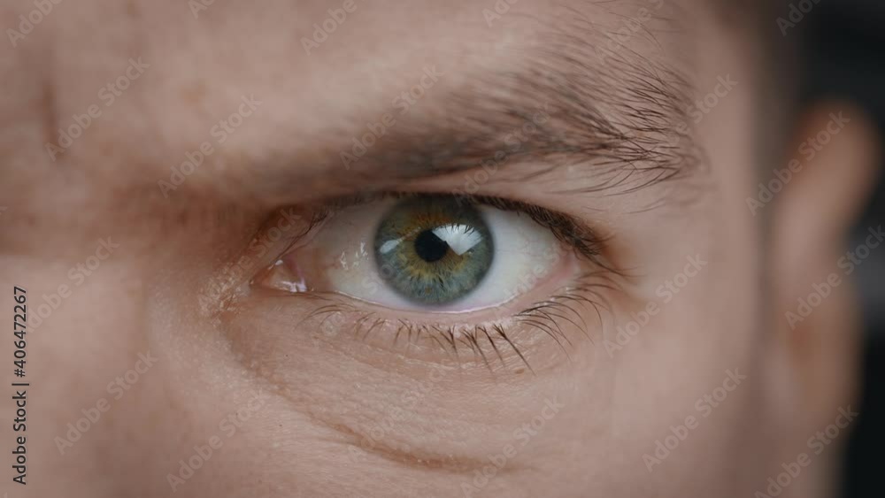Close-up portrait of angry man's eye. Aggressive male's eyes blinking and looking seriously at camera. Close-up portrait of angry man's eye. Aggressive male's eyes blinking and looking seriously at camera.