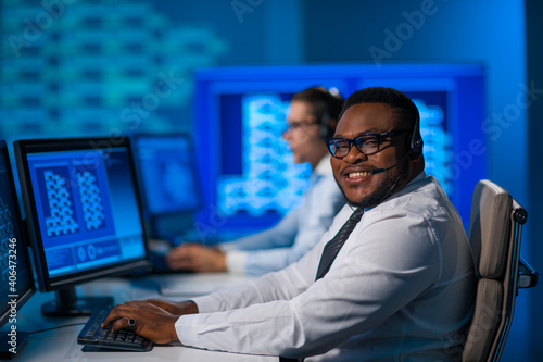 Call-center worker is speaking with the client by headset. Workplace of the african-american support operator.