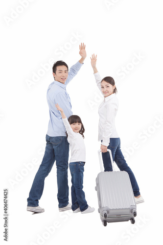 Portrait of mother pulling valise holding up arms 
