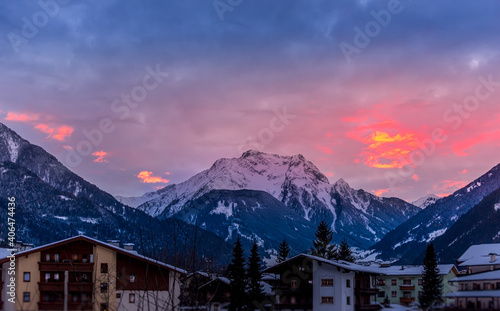 Unfocused ski lodge below a stunning sunset with snowcapped mountains