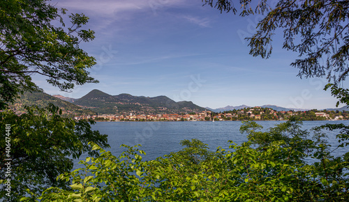 Looking through trees across a lake to a pretty Italian town