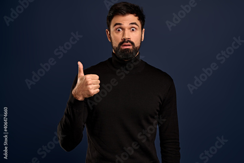 Impressed handsome young man showing thumbs-up and nod in agreement, look excited as hear wonderful idea, approve something good, think you made excellent choice, Pacific Blue background