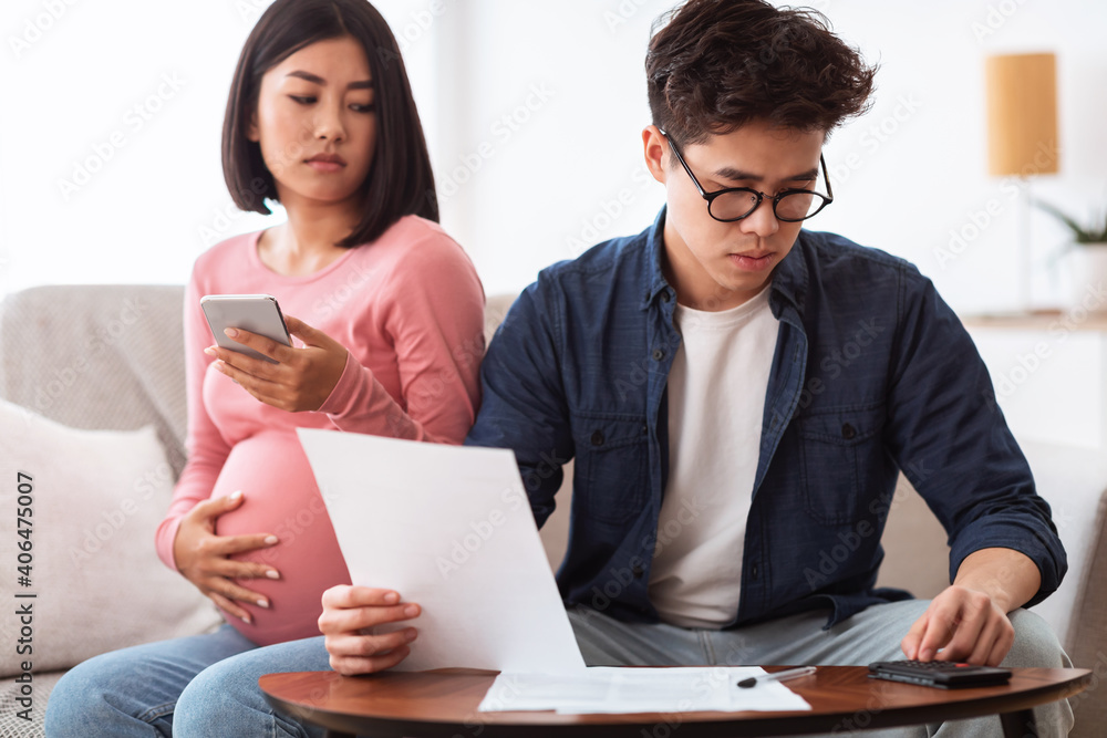 Concerned Asian Couple Calculating Expenses Looking At Bills At Home Concerned Asian Couple Calculating Expenses Looking At Bills At Home